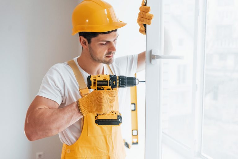 Handyman in yellow uniform installs new window