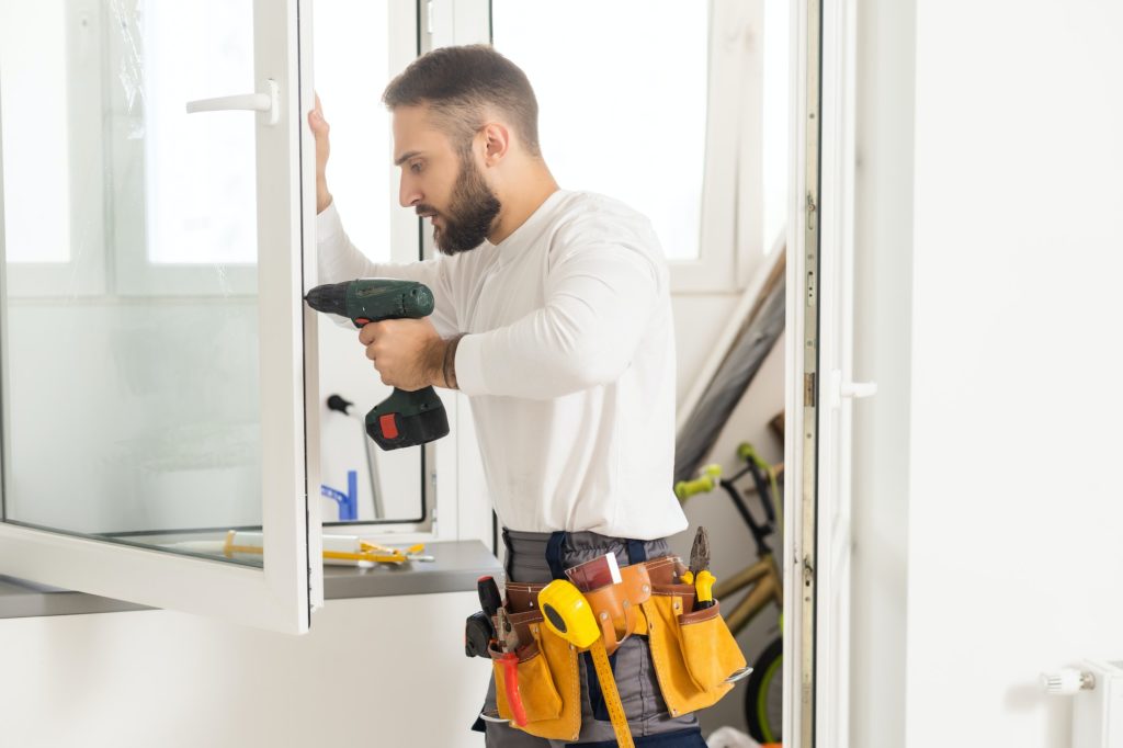 handsome young man installing bay window in a new house construction site.